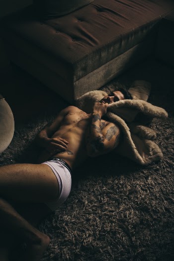 Photo of Topless Man Lying on Carpet