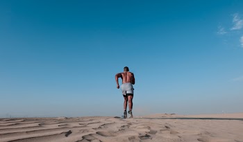 Photo of Topless Man Running on Sand