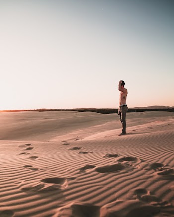 Photo of Topless Man Standing on Desert