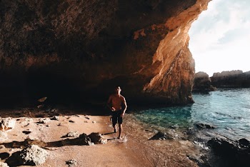 Photo of Topless Man Walking on Seashore