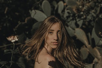 Photo of Topless Woman With Her Hair Flying Standing In Front of Green-leafed Plants
