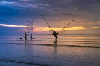 Photo of Two Men Holding Nets in Ocean