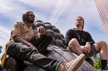 Photo of Two Men in Long Sleeved Shirts  Sitting on Gray Statue