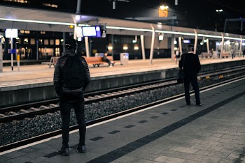 Photo of Two Men Standing Near Railway Station 