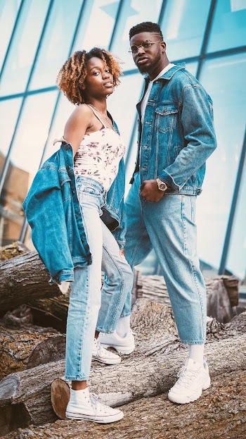 Photo of Two People Standing on Wooden Logs While Wearing Blue Denim Jacket