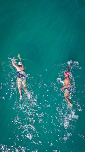 Photo of Two People Swimming on Body of Water