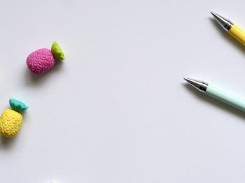 Photo of Two Purple and Yellow Pineapple Erasers Near Pens