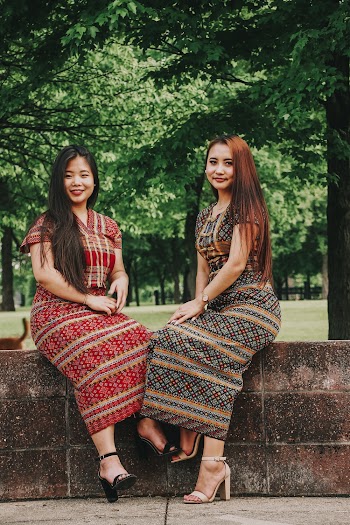 Photo of Two Smiling Women Sitting on Stone Wall