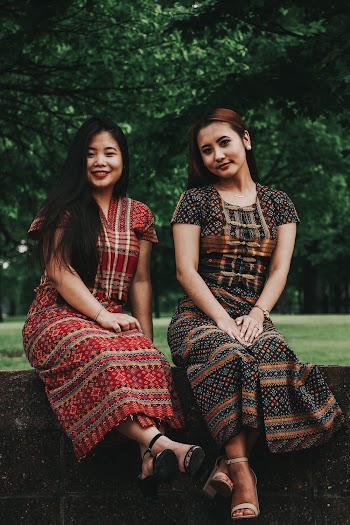 Photo of Two Smiling Women Sitting on Stone Wall