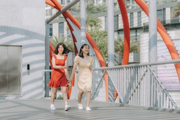 Photo of Two Smiling Women Walking While Holding Hands