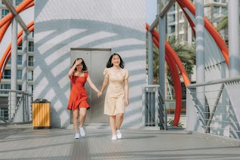 Photo of Two Smiling Women Walking While Holding Hands
