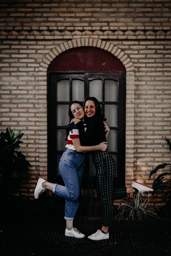 Photo of Two Women Embracing by the Window