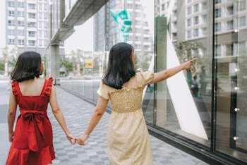 Photo of Two Women Holding Hands While Walking