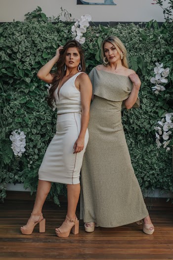 Photo of Two Women Posing in Front of Green Leafed Hedge Wall