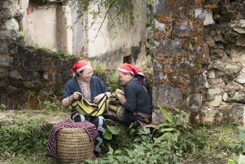 Photo of Two Women Sitting Beside Wall