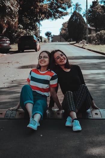 Photo of Two Women Sitting on Road