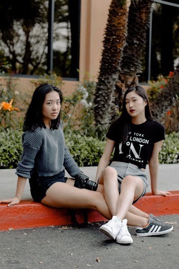 Photo of Two Women Sitting on the Curb Posing