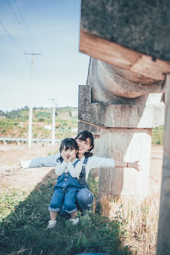 Photo of Woman and Girl Sitting Under Concrete Bridge