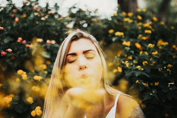 Photo of Woman Blowing Yellow Petaled Flowers