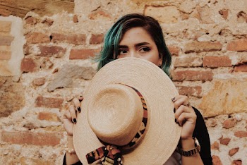 Photo of Woman Covering Her Face With Brown Sun Hat Standing In Front of  Brick Wall