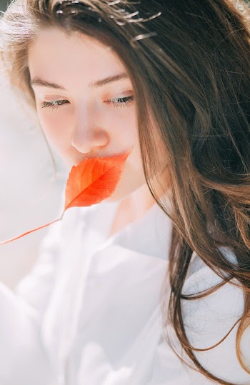 Photo of Woman Covering Her Mouth With a Leaf
