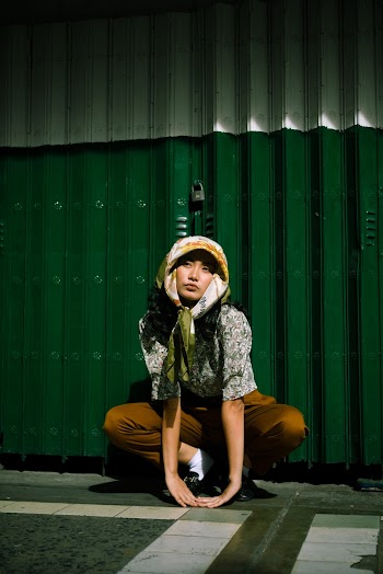 Photo of Woman Crouching Near Shutter Door
