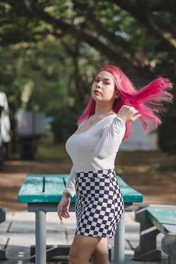 Photo of Woman Flipping Her Pink Hair Posing Next t Park Bench