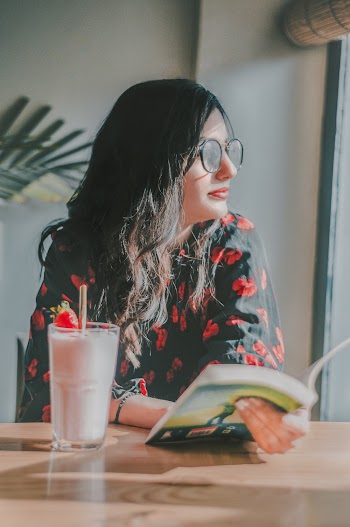 Photo of Woman Holding a Book While Looking Away
