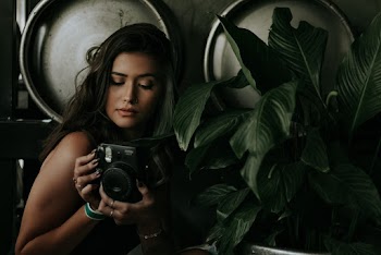 Photo of Woman Holding Black Camera Near Dark Green Plants