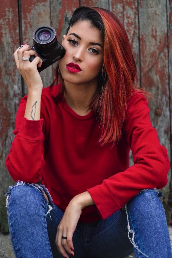 Photo of Woman Holding Camera While Sitting on Ground