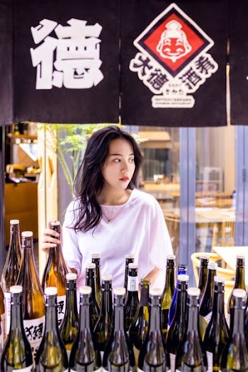 photo of woman holding green translucent glass bottle