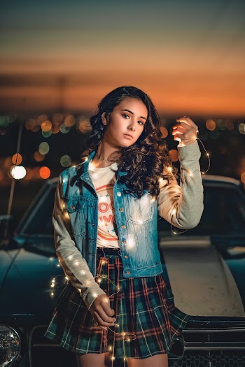Photo of Woman Holding String Lights Posing In Front of Car at Night