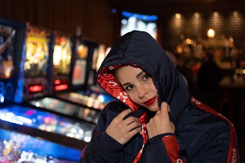 Photo of Woman in a Black and Red Jacket at an Arcade
