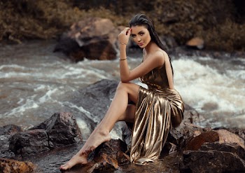Photo of Woman in a Gold Gown Sitting on a Rock by the River