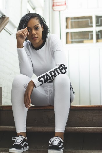 Photo of Woman in All White Starter Outfit and Black Vans Sitting on Stairs Posing
