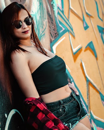 Photo of Woman in Black Crop Top and Distressed Black Denim Short Shorts Leaning on Graffiti Wall