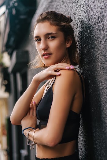 Photo of Woman in Black Crop Top Leaning on Black Wall