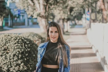 Photo of Woman in Black Cropped Top and Blue Denim Jacket Standing on Sidewalk