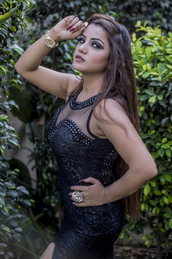 Photo of Woman in Black Dress Posing by Green-leafed Plants