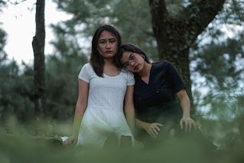 Photo of Woman in Black Dress Resting Her Head on Her Friends Shoulder in White Dress