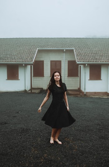 Photo of Woman in Black Dress Standing Outdoors In Front of a White House