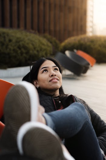 Photo of Woman in Black Jacket and Blue Denim Jeans Lying on Chair While Looking Up
