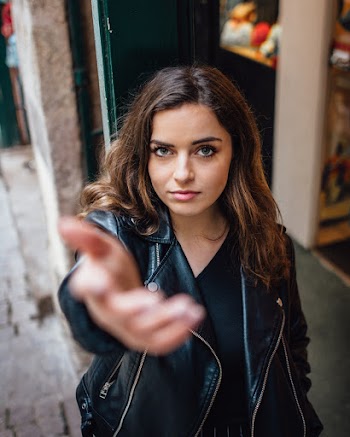 Photo of Woman in Black Leather Jacket Posing with Her Hand Out