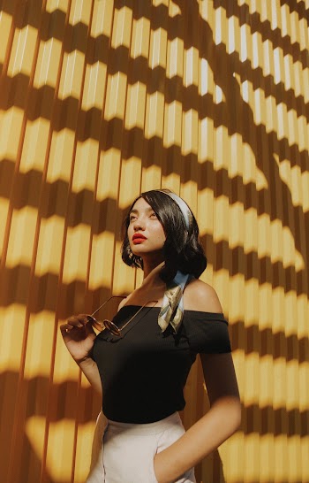 Photo of Woman in Black Off-shoulder Top Posing In Front of Yellow Wall