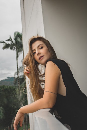 Photo of Woman in Black Outfit Leaning on Stone Railing