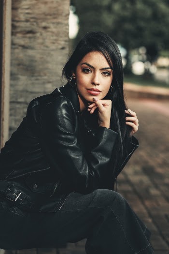 Photo of Woman in Black Outfit Sitting with Hand on Chin