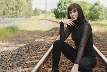 Photo of Woman in Black Outfit Squat Posing in Middle of Train Track