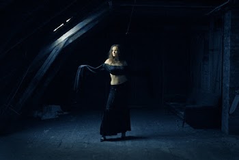 Photo of Woman in Black Outfit Standing in Dark Abandoned Building Posing While Looking Away