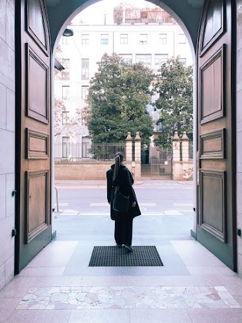 Photo of Woman In Black Outfit Standing Near Big Brown Opened Door