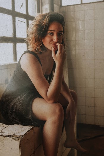 Photo of Woman in Black Sleeveless Dress Sitting Alone on Tiled Counter